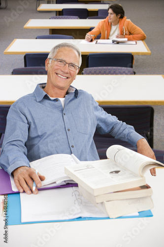 Photo: Portrait of smiling senior man studying in library Portrait of smiling senior man studying in library
