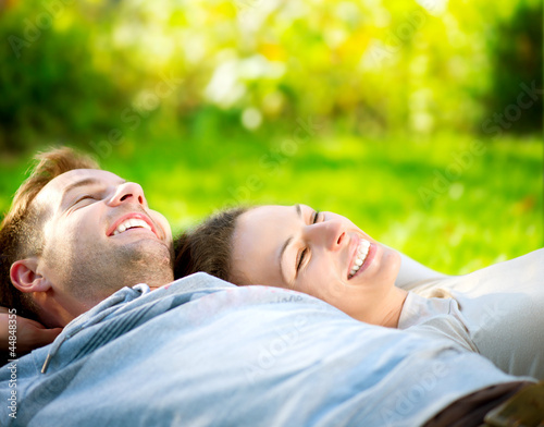 Foto: Park. Young Couple Lying on Grass Outdoor Park. Young Couple Lying on Grass Outdoor