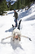 Man pulling wife on sled in snow covered wilderness