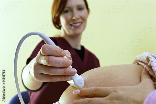 Photo: Close up of woman receiving ultrasound from nurse Close up of woman receiving ultrasound from nurse
