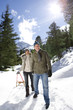 Portrait of happy senior couple with sled in snowy, sunny woods