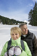 Senior couple standing in snow with mountain in background