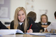Smiling girl doing homework at desk in classroom