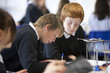 Boys taking notes near Bunsen burner in science class