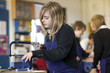 Girl using saw in school workshop