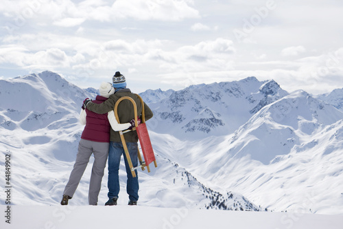 Photo: Senior couple with sled hugging on mountain top Senior couple with sled hugging on mountain top