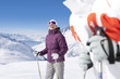 Foto: Smiling woman wearing ski goggles and holding ski poles on snowy mountain Smiling woman wearing ski goggles and holding ski poles on snowy mountain