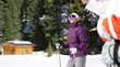 Foto: Smiling woman wearing ski goggles and holding ski poles in snow outside cabin Smiling woman wearing ski goggles and holding ski poles in snow outside cabin