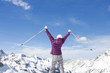 Foto: Woman holding ski poles with arms outstretched on snowy mountain top Woman holding ski poles with arms outstretched on snowy mountain top