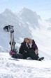 Foto: Smiling senior couple with skis and water bottle sitting on snowy mountain Smiling senior couple with skis and water bottle sitting on snowy mountain
