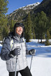 Smiling man with ski poles trekking in snowy woods