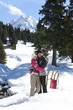 Portrait of smiling couple hugging in snow woods below mountain