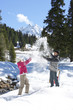 Playful couple throwing snow in woods below mountain