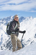 Portrait of smiling woman with backpack and ski poles trekking on snowy mountain