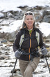 Portrait of smiling woman with ski poles crossing stream