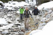 Smiling seniors with ski poles walking along stream
