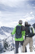 Couple with backpacks and ski poles on snowy mountain
