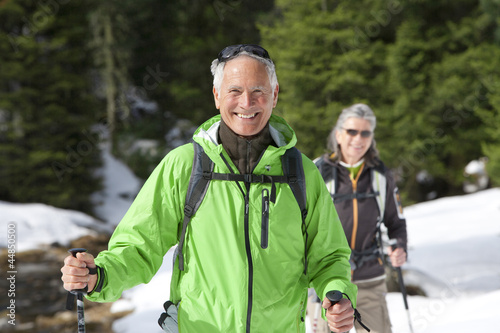 Photo: Portrait of smiling couple with ski poles trekking in snowy woods Portrait of smiling couple with ski poles trekking in snowy woods
