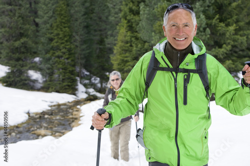 Photo: Portrait of smiling couple with ski poles trekking in snowy woods Portrait of smiling couple with ski poles trekking in snowy woods