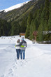 Couple walking in snowy woods outside cabins