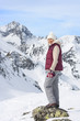 Portrait of smiling senior woman standing on rock on snowy mountain