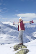 Photo: Portrait of smiling senior woman standing with arms outstretched on rock on snowy mountain Portrait of smiling senior woman standing with arms outstretched on rock on snowy mountain