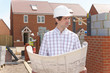 Architect holding blueprints at housing construction site