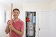 Photo: Portrait of smiling man with copper pipes in front of boiler in closet Portrait of smiling man with copper pipes in front of boiler in closet