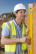 Foto: Bricklayer holding level tool against brick wall Bricklayer holding level tool against brick wall