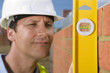 Foto: Close up of bricklayer holding level tool against brick wall Close up of bricklayer holding level tool against brick wall