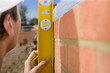 Foto: Close up of bricklayer holding level tool against brick wall Close up of bricklayer holding level tool against brick wall
