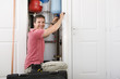Portrait of smiling handyman fixing boiler in closet