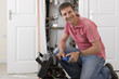Foto: Portrait of smiling handyman with wrench kneeling before toolbox in front of boiler in closet Portrait of smiling handyman with wrench kneeling before toolbox in front of boiler in closet