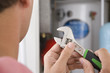 Foto: Close up of handyman holding wrench in front of boiler in closet Close up of handyman holding wrench in front of boiler in closet