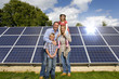 Happy family standing together near large solar panels