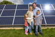 Smiling family standing together near large solar panels