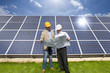 Photo: Technicians holding blueprints talking near large solar panels Technicians holding blueprints talking near large solar panels