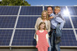 Smiling family standing together near large solar panels