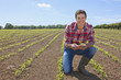 Portrait of smiling farmer holding corn seedling in field