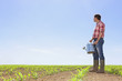 Farmer with watering can in field of corn seedlings
