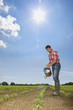 Farmer watering corn seedlings in field with watering can