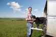 Portrait of smiling farmer petting dog on tailgate of truck in field
