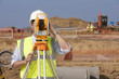 Surveyor looking through theodolite at construction site