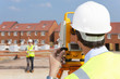 Surveyor looking towards co-worker through theodolite at construction site