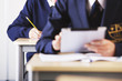 Photo: Student in school uniform using digital tablet at desk in classroom Student in school uniform using digital tablet at desk in classroom