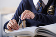 Photo: Close up of male student in school uniform using drawing compass at desk in classroom Close up of male student in school uniform using drawing compass at desk in classroom