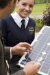 Photo: Portrait of smiling female student holding solar panel with teacher Portrait of smiling female student holding solar panel with teacher