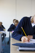 Photo: Students in school uniforms taking exam at desk in classroom Students in school uniforms taking exam at desk in classroom