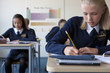 Photo: Female student in school uniform taking exam at desk in classroom Female student in school uniform taking exam at desk in classroom
