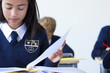 Photo: Female student in school uniform taking exam at desk in classroom Female student in school uniform taking exam at desk in classroom